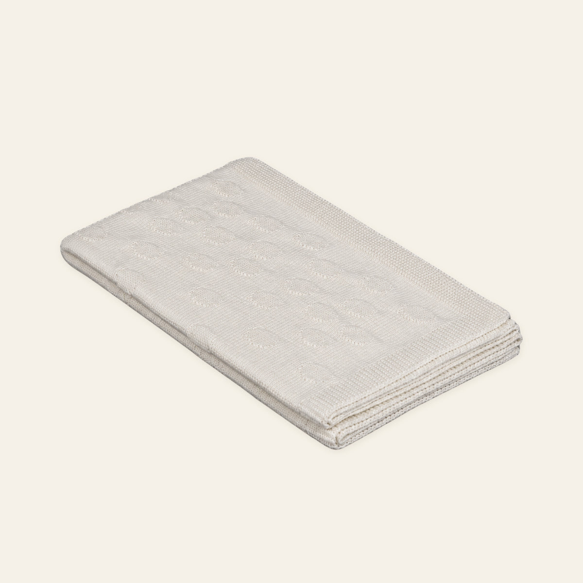 Pislak Alex baby knitted blanket in cream, neatly folded in a studio view showing its fine dotted knit pattern.