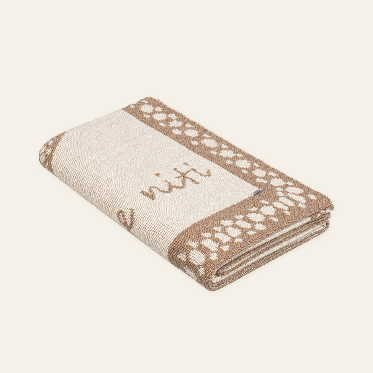Pislak Toplina alpaca-blend throw in sand and cream, neatly folded in a studio view showing its decorative knitted pattern.