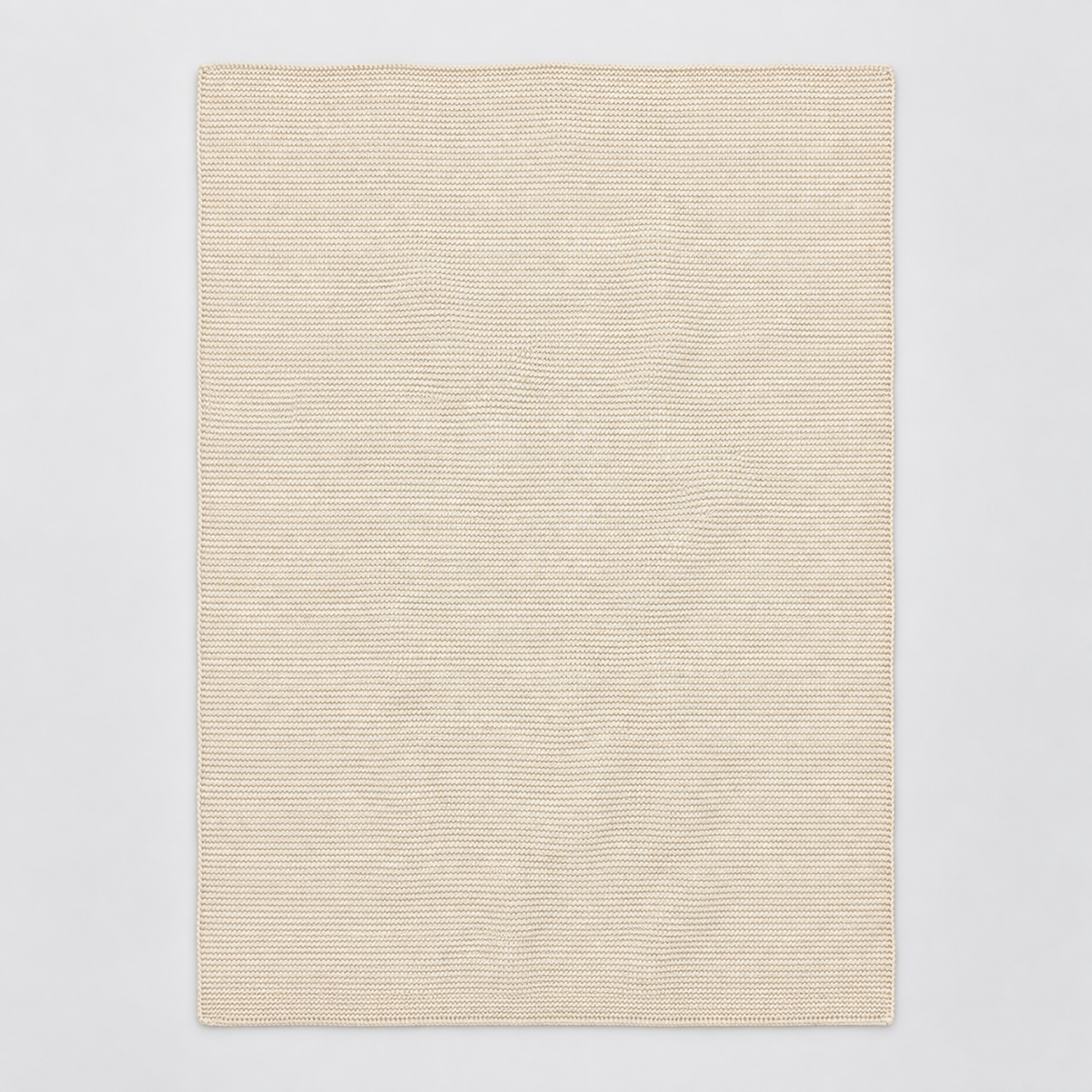 Zarja cotton blanket in cream, shown fully unfolded with fine garter-knit rows and a simple narrow edge.
