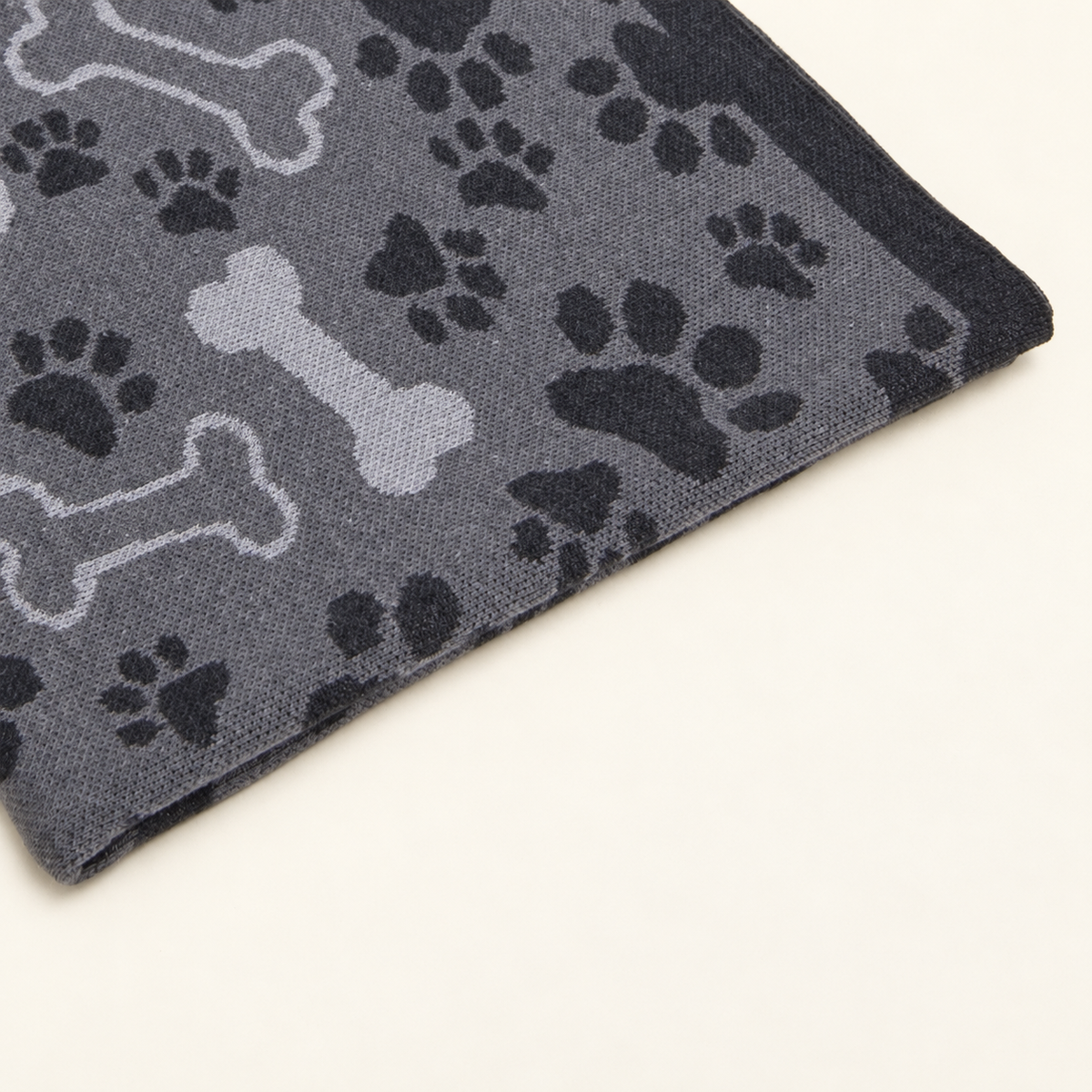 Čarli blanket in grey, detail of paw prints, bone motifs and the dark border.