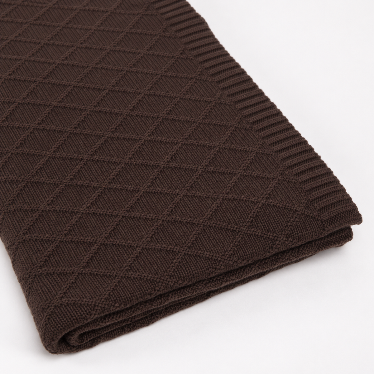 KARO throw in dark brown, detail of the fine diamond knit, ribbed border and folded layers.
