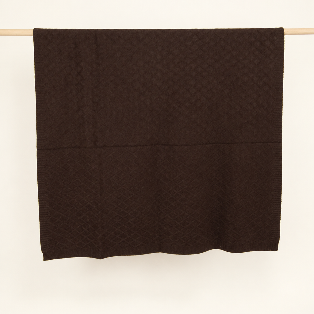 KARO throw in dark brown, hanging folded to show its diamond knit and lower border.