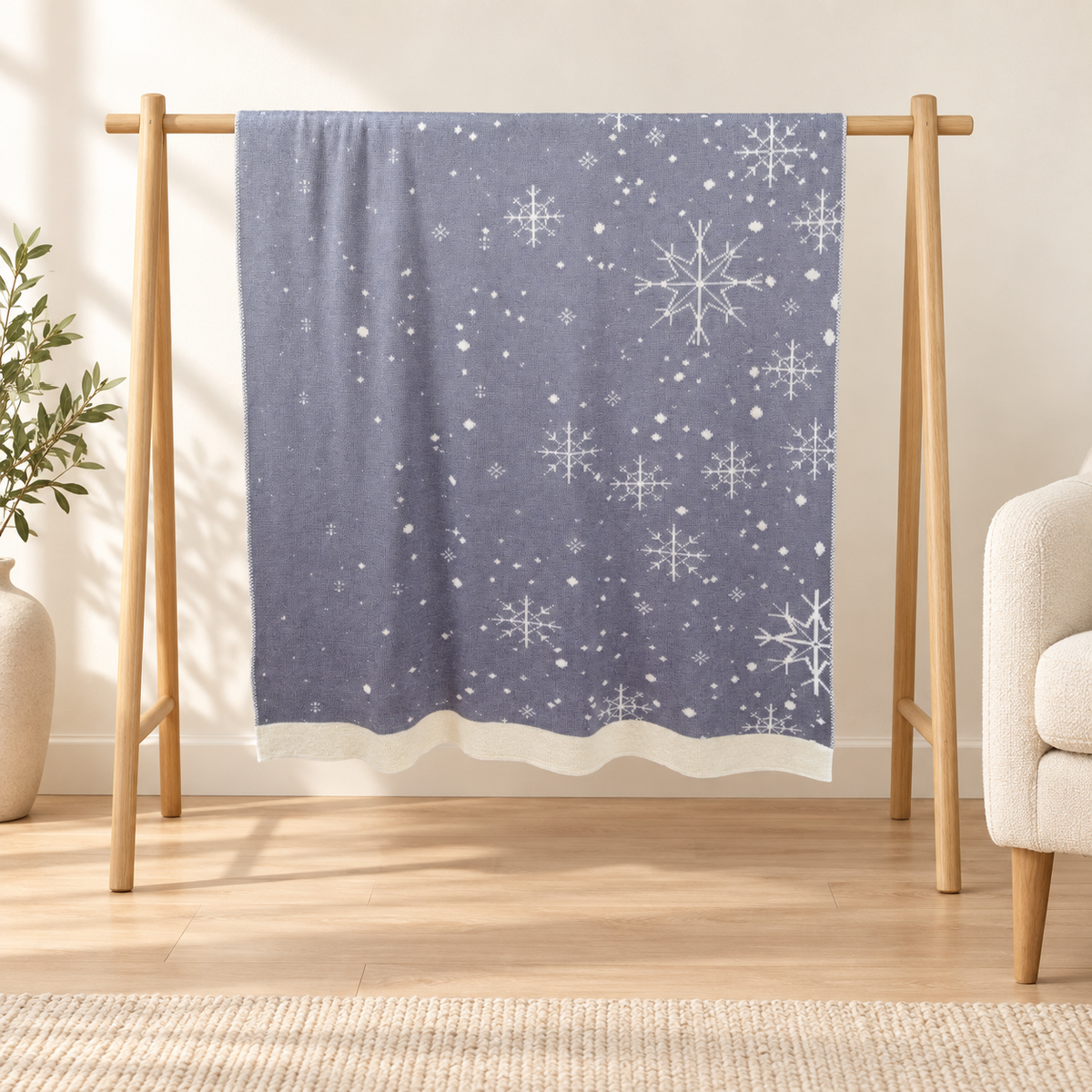 Sneg blanket in grey and cream, hanging on a rack with snowflake motifs and scattered dots visible.