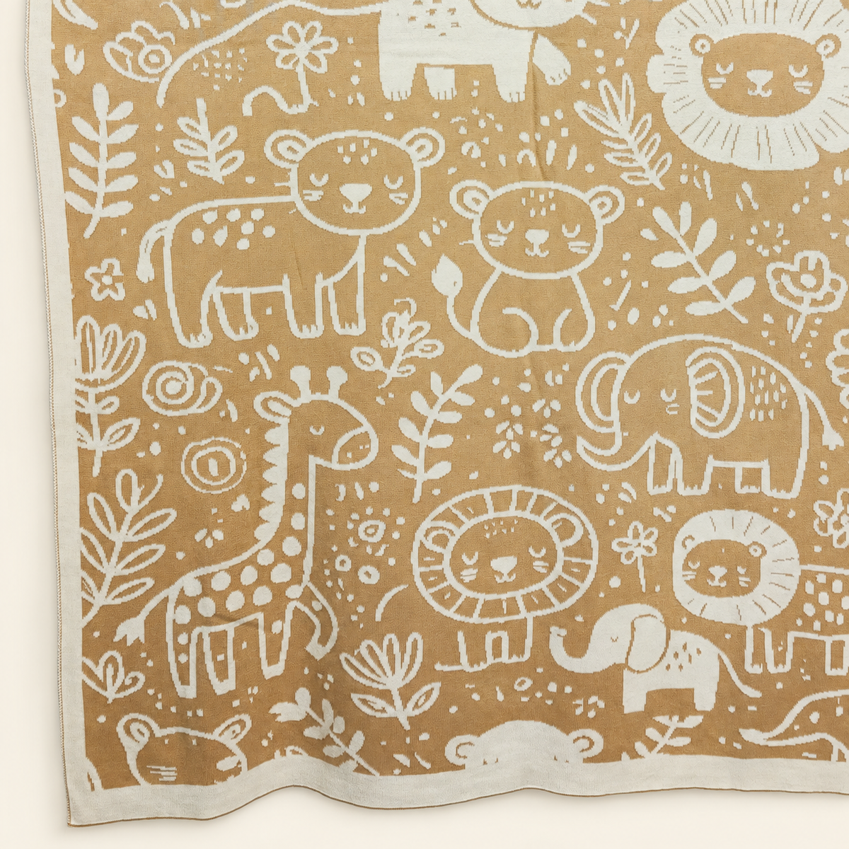 Svit blanket in sand and cream, detail of animal motifs and the lower knitted edge.