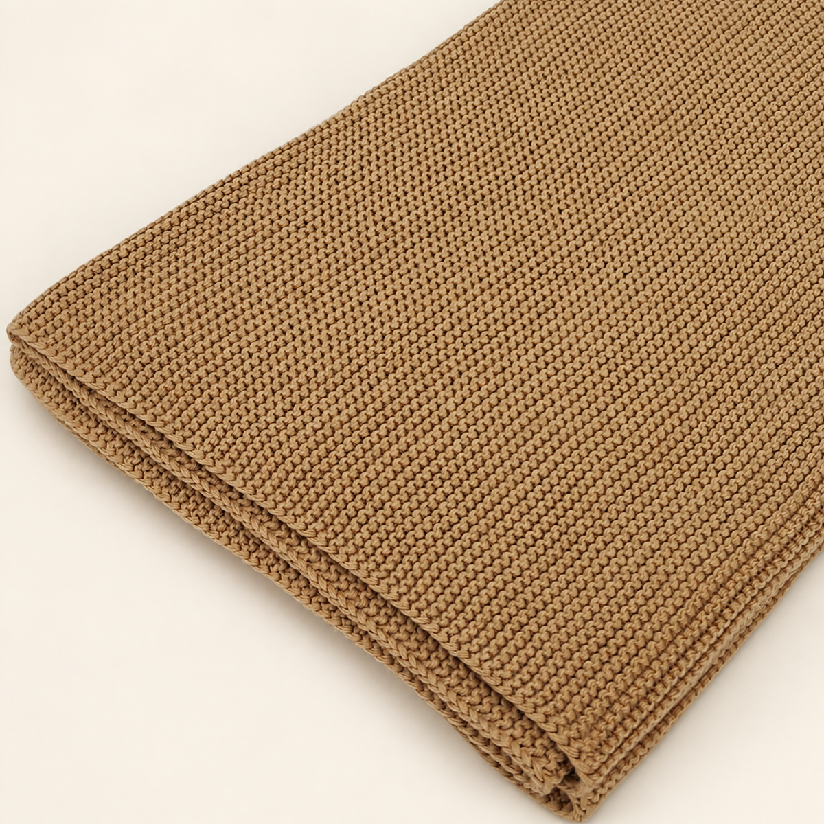 Zarja blanket in sand, detail of fine garter-knit rows, a simple edge and thin folded layers.